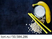 Homemade antioxidant banana smoothie with oat flakes on dark vintage background. Top view, copy space. Стоковое фото, агентство Ingram Publishing / Фотобанк Лори