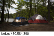 Two nylon tents in a campsite next to a lake surrounded by forest. Стоковое фото, агентство Ingram Publishing / Фотобанк Лори