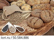 Seeded bread roll selection with wheat sheaths, rye grain in a hessian sack wiith chia, sunflower and caraway seed on an olive wood board. Стоковое фото, агентство Ingram Publishing / Фотобанк Лори