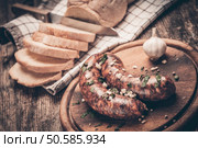 Closup of homemade sausages on woodn cutting board with garlic and parsley and cutted bread. Стоковое фото, агентство Ingram Publishing / Фотобанк Лори