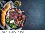 Juicy meat appetizer with spicy baguette bread on dark backgroun with blank space . Стоковое фото, агентство Ingram Publishing / Фотобанк Лори