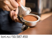 Barista pressing ground coffee into portafilter by tamper to making coffee. Стоковое фото, агентство Ingram Publishing / Фотобанк Лори