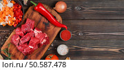 Ingredients for making goulash or stew, stew or gyuvech: top view of raw beef meat, herbs, spices, paprika, vegetables on a dark wooden background. Space for text, composition for flat lay. Стоковое фото, агентство Ingram Publishing / Фотобанк Лори