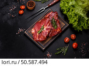 Raw flank beef steak and ingredients for cooking on a wooden board, close up. Raw organic marbled beef steaks with spices on a wooden cutting board. Стоковое фото, агентство Ingram Publishing / Фотобанк Лори