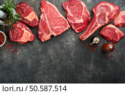 Raw prime steaks. Variety of fresh black angus prime meat steaks T-bone, New York, Ribeye, Striploin, Tomahawk on black or gray stone background. Set of various classic steaks. Top view, copy space. Стоковое фото, агентство Ingram Publishing / Фотобанк Лори