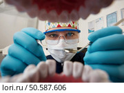Healthy teeth and smile. Serious doctor directly into the camera. Dentist sitting in the dentist for dental chair and holding a dental drill in hand. Стоковое фото, агентство Ingram Publishing / Фотобанк Лори