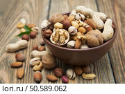 Mixed nuts in a bowl on a wooden background . Стоковое фото, агентство Ingram Publishing / Фотобанк Лори