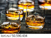 Glass of scotch whiskey and ice on a black wooden background,selective focus. Стоковое фото, агентство Ingram Publishing / Фотобанк Лори