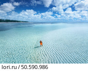Aerial view of man on the sandbank in ocean, white sand, blue sea during low tide at sunrise in summer. Zanzibar island. Top drone view of guy, sand spit, lagoon, clear water, sky with clouds. Travel. Стоковое фото, агентство Ingram Publishing / Фотобанк Лори