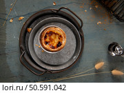 A single Pastel de Nata, resting on a rustic metal tray, with a hint of cinnamon sprinkled on top. Стоковое фото, агентство Ingram Publishing / Фотобанк Лори