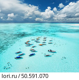 Aerial view of colorful boats and yachts in transparent water on sunny summer day. Mnemba island, Zanzibar. Top view of sandbank in low tide, blue sea, swimming people, yachts, sky with clouds. Ocean. Стоковое фото, агентство Ingram Publishing / Фотобанк Лори