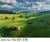 Aerial view of the largest high-altitude alpine meadow in europe, alpe di siusi, wooden huts nestled in a lush green landscape at sunset. Top view of  houses in mountains. Summer in Dolomites, Italy. Стоковое фото, агентство Ingram Publishing / Фотобанк Лори