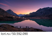 Mountain peaks mirrored in a tranquil alpine lake in autumn at sunset. Lake Bianco, Switzerland in fall. Colorful landscape with mountains, reflection in water, purple sky at dusk.  Swiss alps	. Стоковое фото, агентство Ingram Publishing / Фотобанк Лори