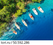 Aerial view of beautiful yachts and boats on the sea at summer sunny day. Fethiye lagoons, Turkey. Top view of bay, luxury yachts, sailboats, clear blue water, beach, green forest. Travel. Yachting. Aerial view of yachts and boats on the sea at sunset in summer. Стоковое фото, агентство Ingram Publishing / Фотобанк Лори