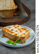 A tempting slice of molotof, a traditional caramelized egg white pudding, generously drizzled with sweet syrup and garnished with fresh mint leaves, sits on a light blue plate. Стоковое фото, агентство Ingram Publishing / Фотобанк Лори