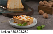 A tempting slice of caramelized molotov pudding, drizzled with sweet caramel and garnished with fresh mint, presented on a small white plate with a golden spoon. Стоковое фото, агентство Ingram Publishing / Фотобанк Лори