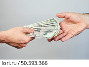 Business closeup of two hands exchanging dollars on grey background. Стоковое фото, агентство Ingram Publishing / Фотобанк Лори