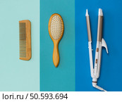 Two wooden combs and an electric Curling iron on a multicolored background. Hair care accessories.. Two wooden combs and an electric Curling iron on a multicolored background. Стоковое фото, агентство Ingram Publishing / Фотобанк Лори