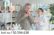 Senior man visits pharmacy and suffers from cough. Girl pharmacist offer help to sick customer. Стоковое видео, видеограф Яков Филимонов / Фотобанк Лори