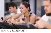 Focused girl works out with stationary bicycle during class at fitness club. Стоковое видео, видеограф Яков Филимонов / Фотобанк Лори