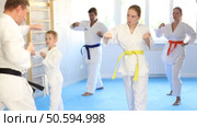 Teen girl with family repeat movements and learn fighting techniques during martial arts lesson. Стоковое видео, видеограф Яков Филимонов / Фотобанк Лори