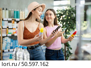 Daughter and mother in summer clothes scans code on sunscreen to check expiration date. Стоковое фото, фотограф Яков Филимонов / Фотобанк Лори