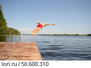 Fit man in swimwear dives off pier into lake. Bold movement and expression of strength. Стоковое фото, фотограф Скоробогатова Е. / Фотобанк Лори