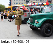 Девушка в солдатской фотме танцет руский танец. 9 мая 2025 г. У автомобиля УАЗ. Редакционное фото, фотограф Анатолий Матвейчук / Фотобанк Лори