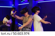 Excited modern young couple with gaming controllers in hands and VR goggles having fun with friends in virtual reality room. Concept of immersive interactive experience. Стоковое видео, видеограф Яков Филимонов / Фотобанк Лори