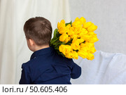 A young, beautiful boy. He carries a huge armful of fresh yellow tulips on his shoulder. The concept of spring and holiday, March 8, International Women's Day. Стоковое фото, фотограф Алина Лебедь / Фотобанк Лори