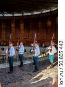 12.08.2024. Russia. Volgograd. Mamayev Kurgan.Uniformed guards in white shirts and red caps hold rifles and stand attentively in formation. Background features a large wall with columns and a visible crowd. Text in a foreign script. Редакционное фото, фотограф Алина Лебедь / Фотобанк Лори