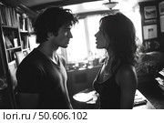 A black and white photograph depicting an emotional moment between a young man and woman in a room interior. The couple are facing each other, their gazes are intense, as if in the midst of a serious conversation or conflict. Soft light from the window highlights facial features and creates contrasting shadows. The atmosphere of the frame is dramatic, cinematic and intimate. Suitable for illustrating themes of love, relationships, emotions, conflict, dialogue and inner tension. Стоковое AI-изображение, AI-художник Анна Кривицкая / Фотобанк Лори