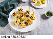 Grilled zucchini rolls filled with cream cheese and tomatoes on a plate on the table. Стоковое фото, фотограф Елена Руй / Фотобанк Лори