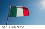 The flag of Italy waving on a flagpole against a clear blue sky with the sun shining in the background. Стоковое AI-видео, аниматор Sergey Grishin / Фотобанк Лори