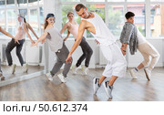 Young man standing performs basic hip hop movements in front of group of students. Стоковое фото, фотограф Яков Филимонов / Фотобанк Лори