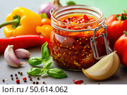 A vibrant glass jar filled with chunky lecho, highlighted by bright lighting and surrounded by fresh peppers and tomatoes. The sealed jar showcases a rich sauce with distinct spices and textures. Стоковое AI-изображение, AI-художник Nart / Фотобанк Лори