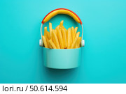 French fries overflowing a colorful lunchbox on a vibrant teal background. Стоковое AI-изображение, AI-художник Иван Рябоконь / Фотобанк Лори