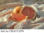 Fresh grapefruits showing juicy texture on soft white fabric. Стоковое AI-изображение, AI-художник Иван Рябоконь / Фотобанк Лори