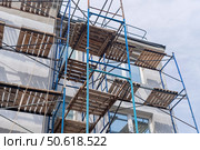 Фасад здания с установленными строительными лесами. Building under construction in scaffolding around the house for cement plastering work on the high outer wall. Стоковое фото, фотограф Татьяна Д / Фотобанк Лори