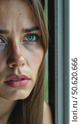 A close-up portrait of a sad, pensive young woman with freckles and blue eyes, looking thoughtfully out a window on a rainy day. Стоковое AI-видео, аниматор Sergey Grishin / Фотобанк Лори