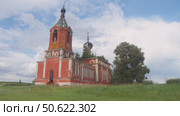 Old Orthodox church stands in the field. domes of bell tower, with a cross, are askew due to dilapidation. wide shot. Стоковое видео, видеограф Strunov David / Фотобанк Лори