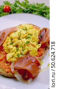 Eastern European breakfast featuring scrambled eggs, smoked ham, parmesan atop crispy toast, garnished with arugula, cherry tomatoes, drizzled with tomato sauce against white surface. Стоковое видео, видеограф Данил Руденко / Фотобанк Лори