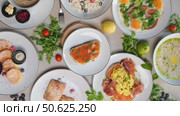 Multiple plates of delicious Eastern European cuisine are artfully arranged on a table, creating a visually appealing spread of various dishes. Стоковое видео, видеограф Данил Руденко / Фотобанк Лори
