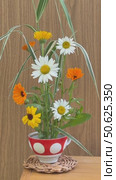 Vertical video of beautiful rural floral arrangement of seasonal fresh garden flowers marigold and daisy on kenzan in cup in traditional ikebana style on wooden wall background. Floral design as hobby. Стоковое видео, видеограф Виктория Катьянова / Фотобанк Лори