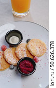 Miniature pancakes nestled on white plate, garnished with fresh berries, cream, jam, alongside orange juice, representing nutritious morning meal. Стоковое видео, видеограф Данил Руденко / Фотобанк Лори