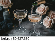 Champagne and red pink roses on a black concrete background. Copy space for text. Valentines drinks for for a pair of lovers. Bartender pours prosecco sparkling wine into glasses. Romance. Wedding Day. Стоковое AI-изображение, AI-художник Марина Демидюк / Фотобанк Лори