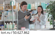 Man scans QR code on box pills label. Female pharmacist offers to choose the right shampoo. Стоковое видео, видеограф Яков Филимонов / Фотобанк Лори
