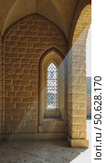 Sunbeams stream through the stone arches of a historic church corridor with a vaulted ceiling and an ornate window, creating a spiritual atmosphere. Стоковое AI-видео, аниматор Sergey Grishin / Фотобанк Лори