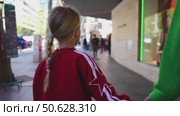 Young girl holding parent hand walking down the street. Стоковое видео, видеограф Данил Руденко / Фотобанк Лори