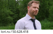Confident Businessman in Natural Setting. Man stands in front of lush green backdrop. Remote working. Portrait of happy mid adult male wearing formal clothes, shirt and tie, glasses. Find inspiration. Стоковое видео, видеограф Марина Демидюк / Фотобанк Лори